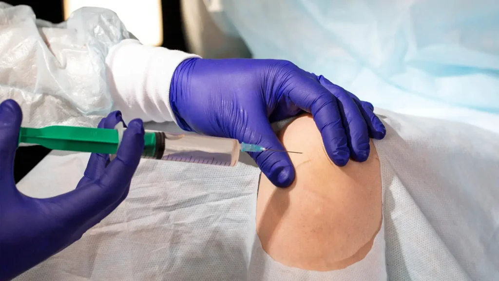 A medical professional administering a knee injection.