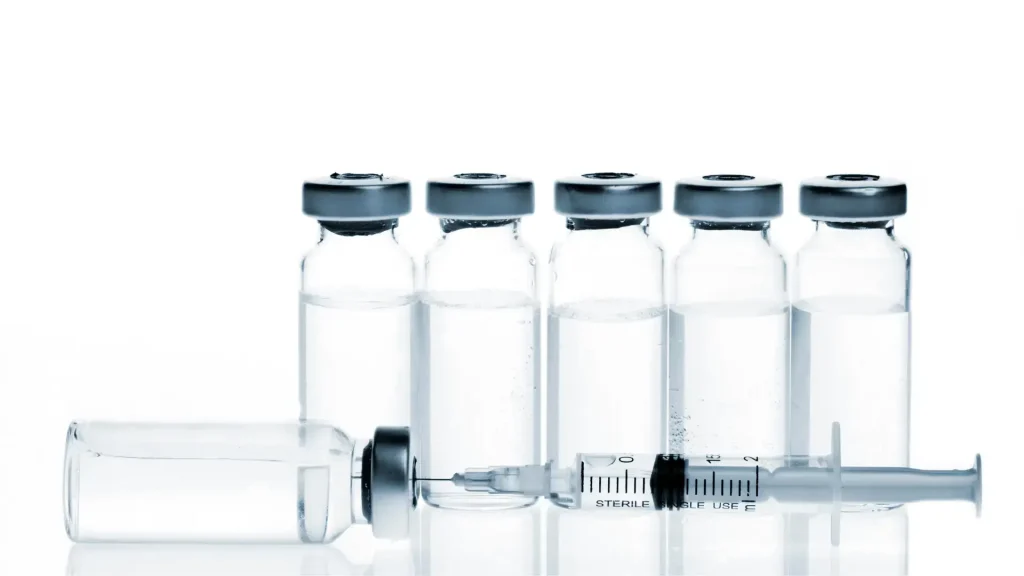 Vials lined up and a syringe needle in a vial.