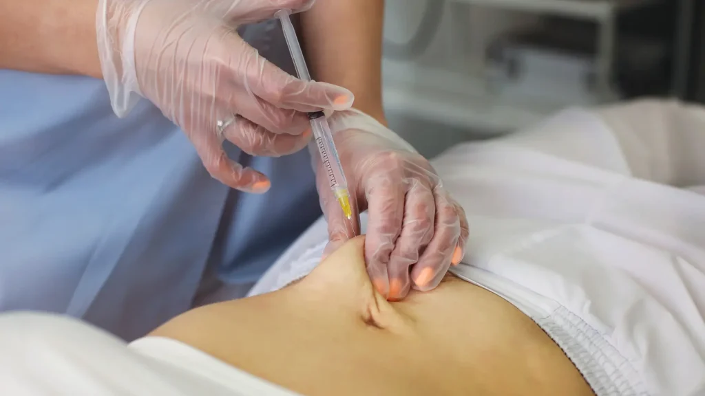 A medical professional administering an injection into the patient's abdomen area.