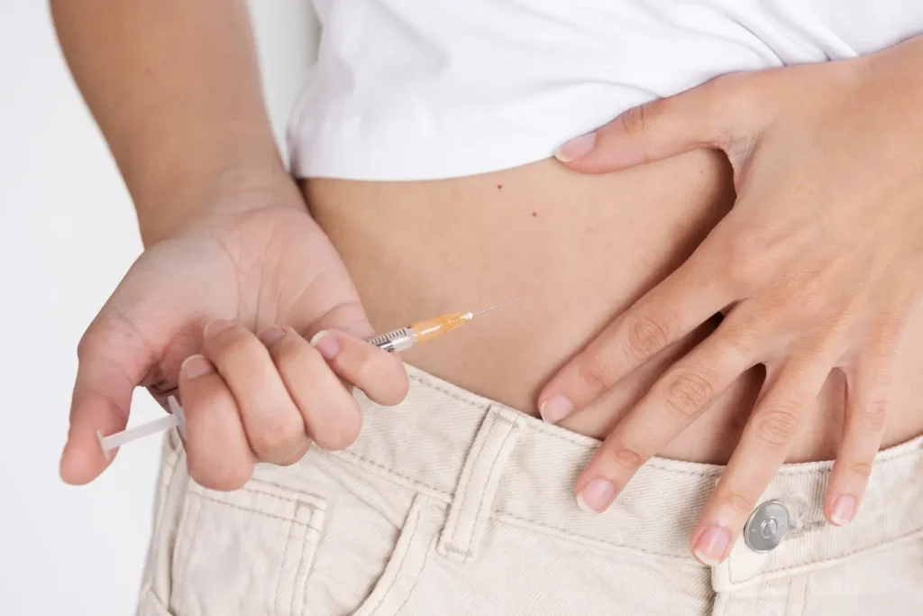 An individual administering an injection into their abdomen area.