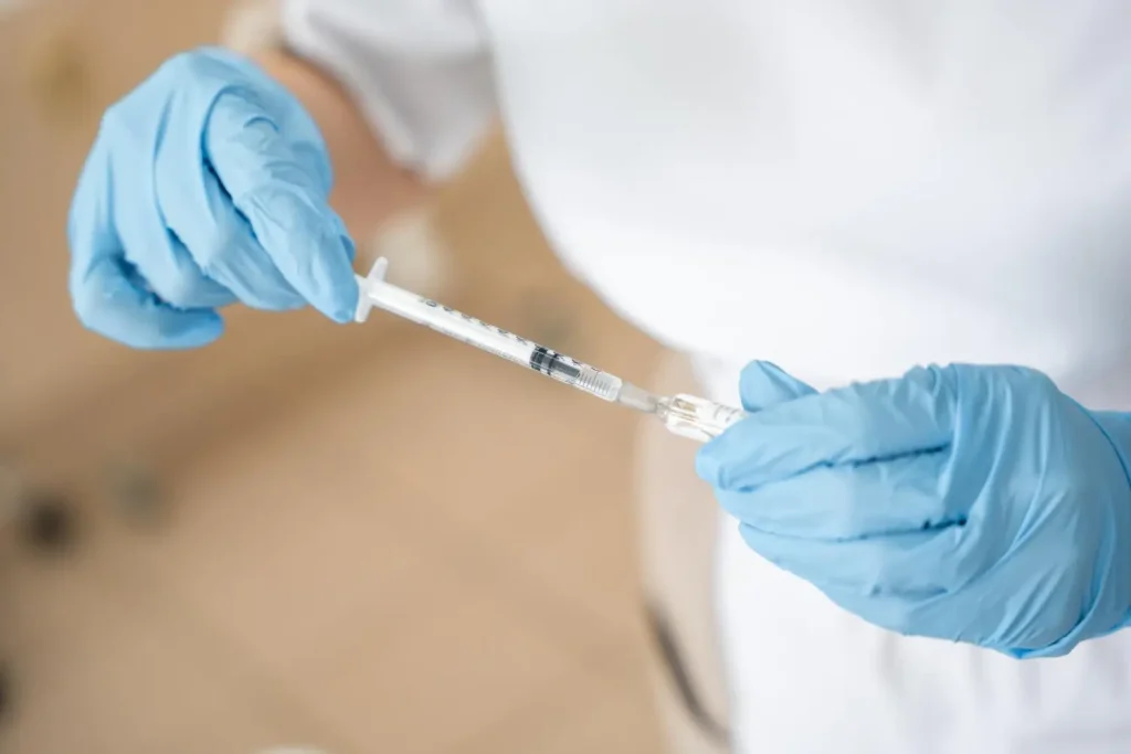 A medical professional preparing an injection before treatment.