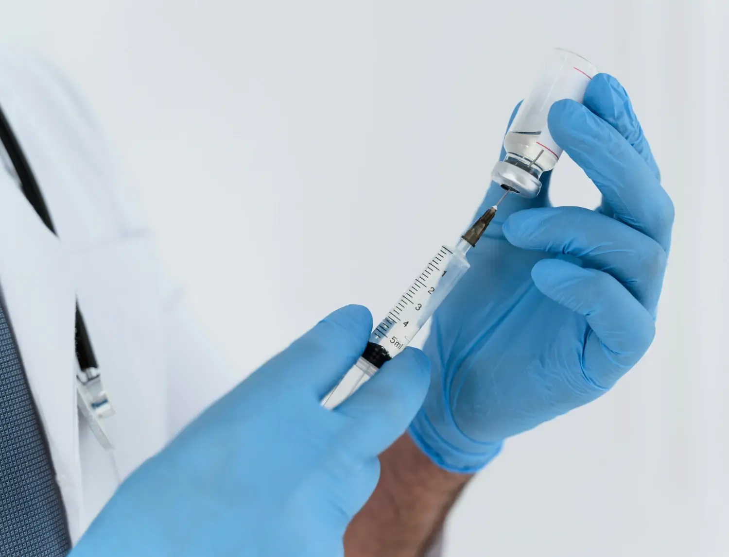 A medical professional transferring the solution from the vial into the injection.