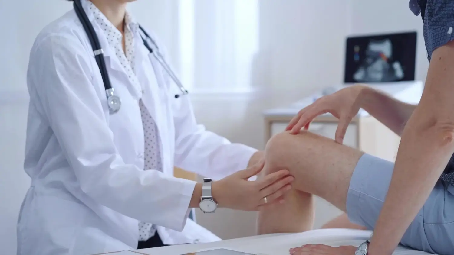A medical professional assessing a patient's knee.