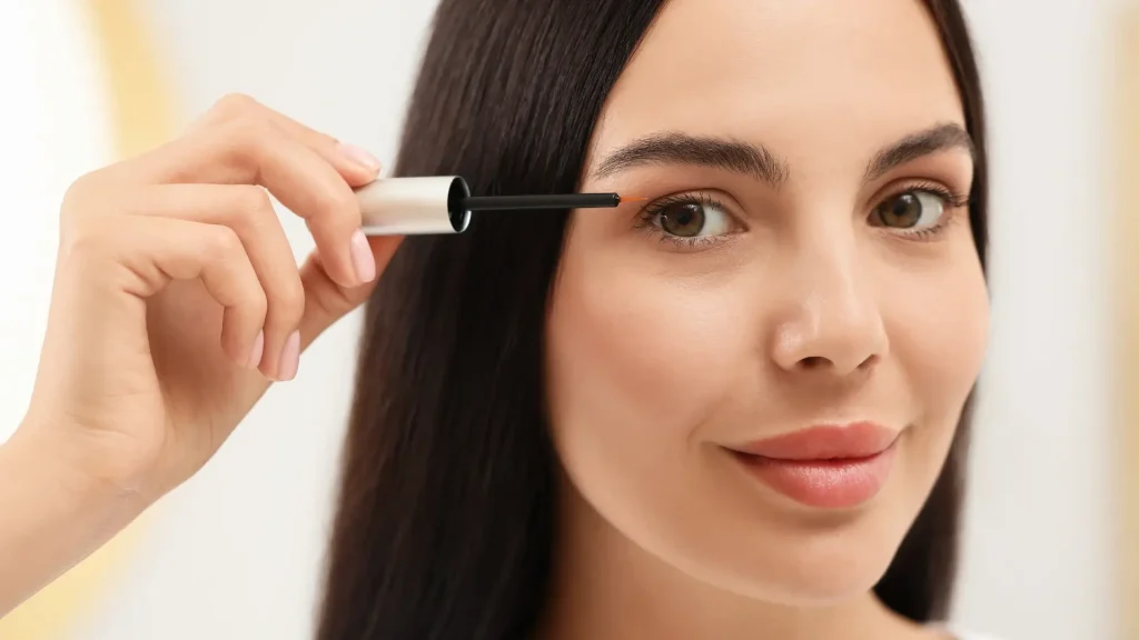 An individual applying a solution into their eyelashes.