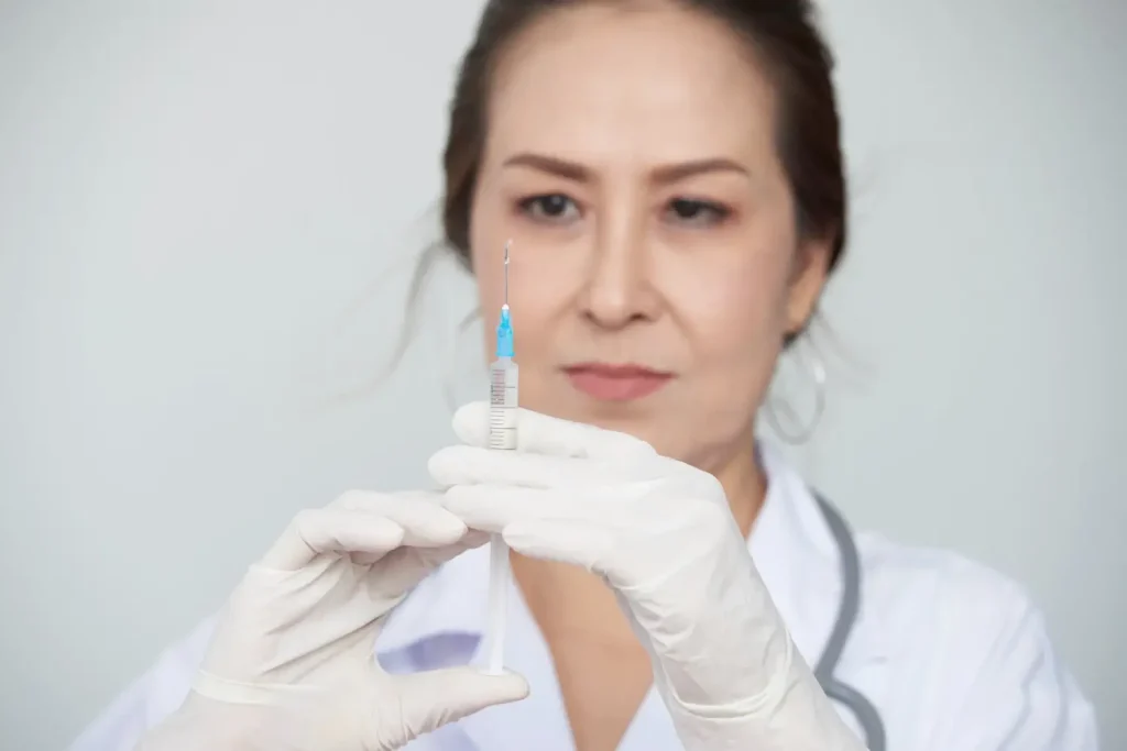 A medical professional holding an injection.