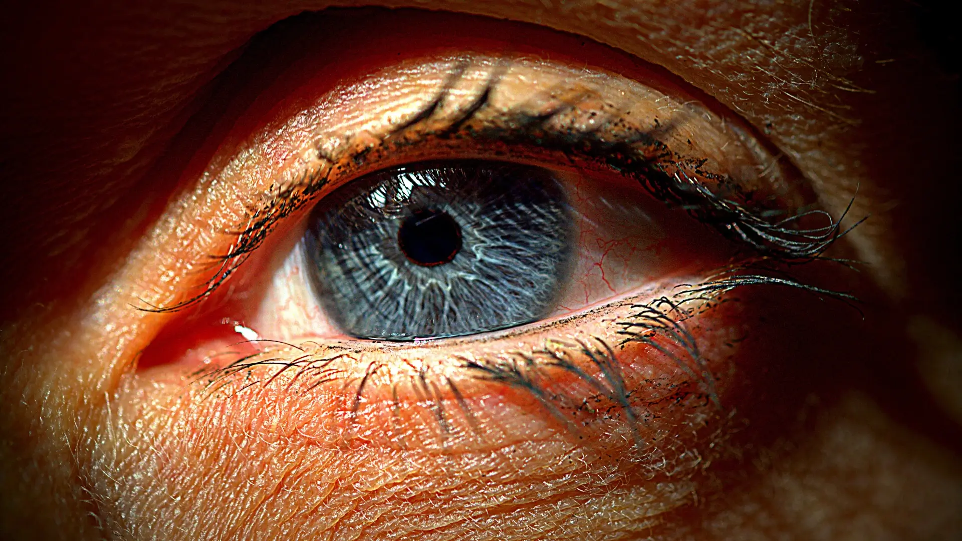 A close-up shot of an individual's eye and eyelashes.