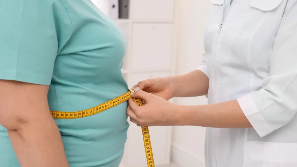 A medical provider measuring an individual's waist.