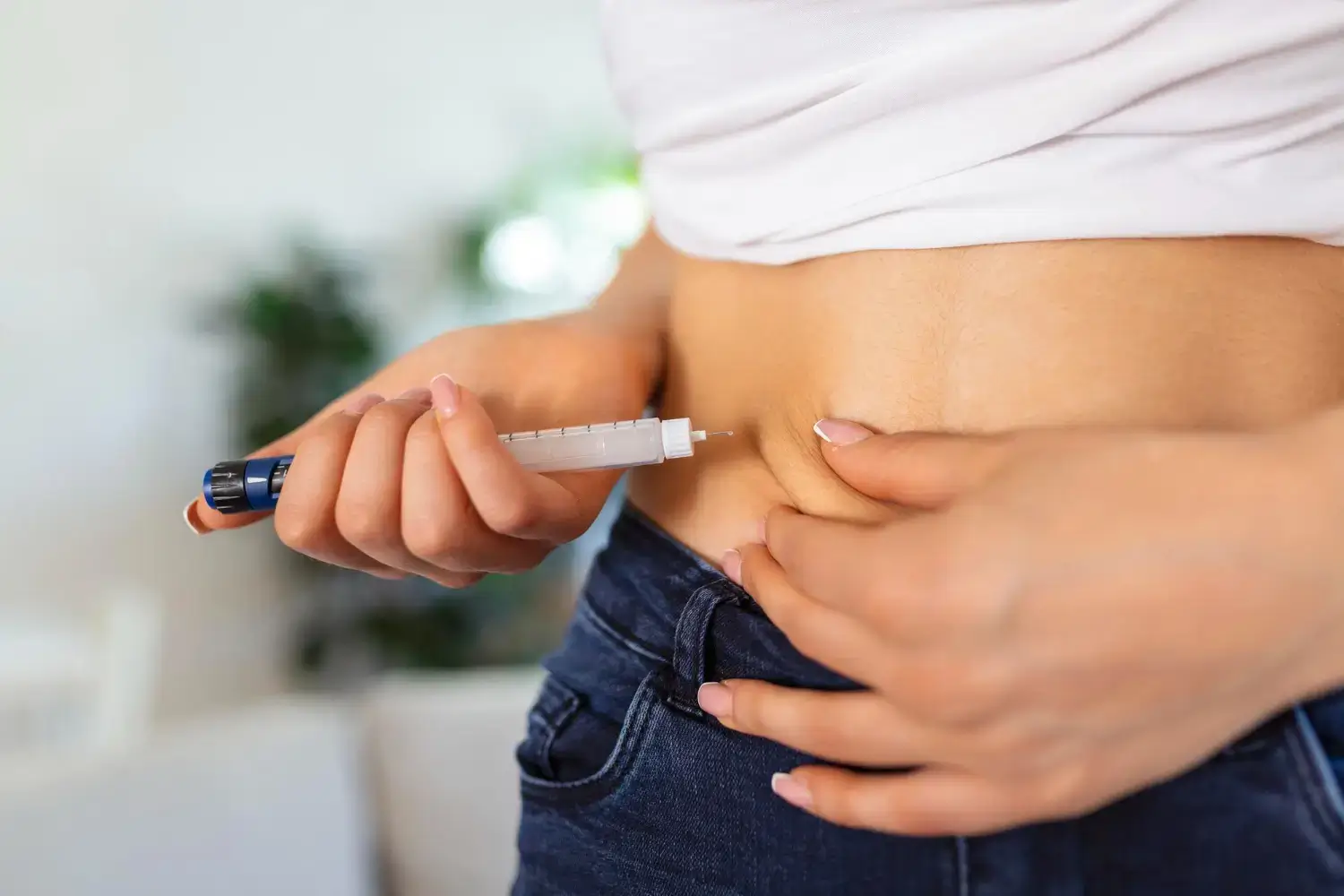 An individual injecting a solution into their abdomen area.