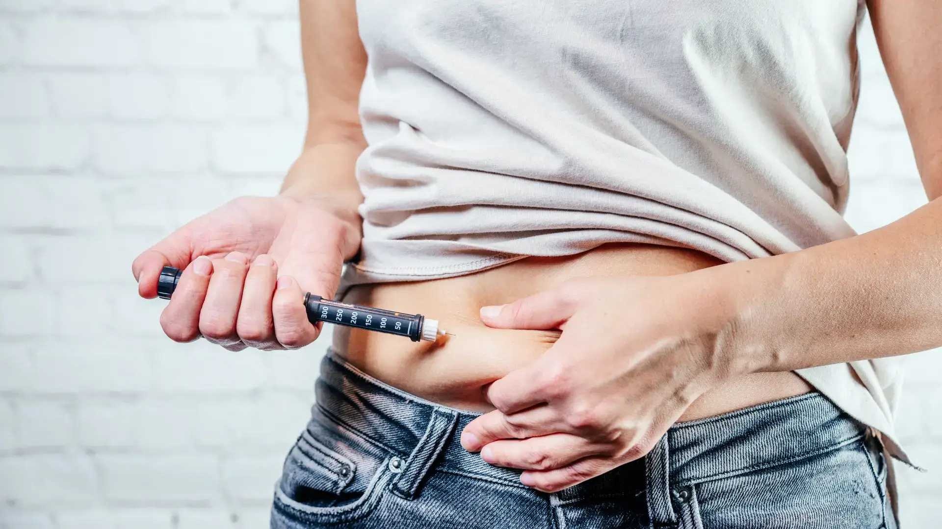An individual administering an injection into their stomach area.