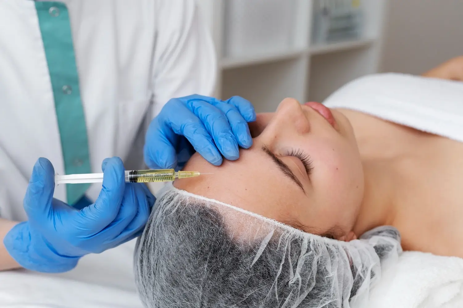An aesthetic professional administering an injection into the patient's forehead.
