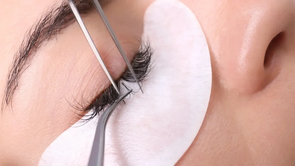 A professional administering lash extensions for an individual.