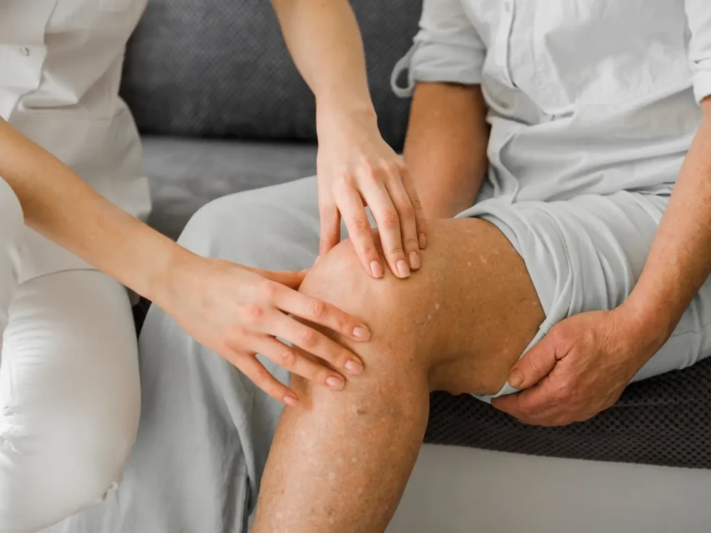 A medical practitioner examining the patient's knee.