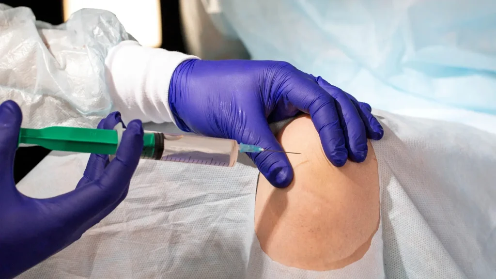 A medical professional administering a knee injection.