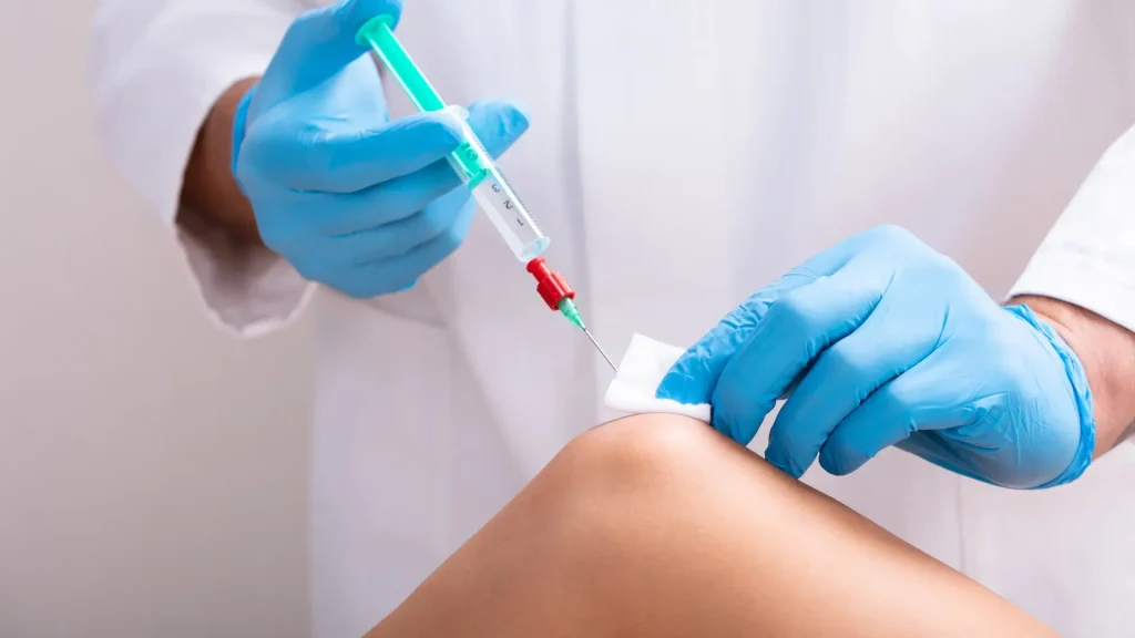 A medical professional administering a knee injection.