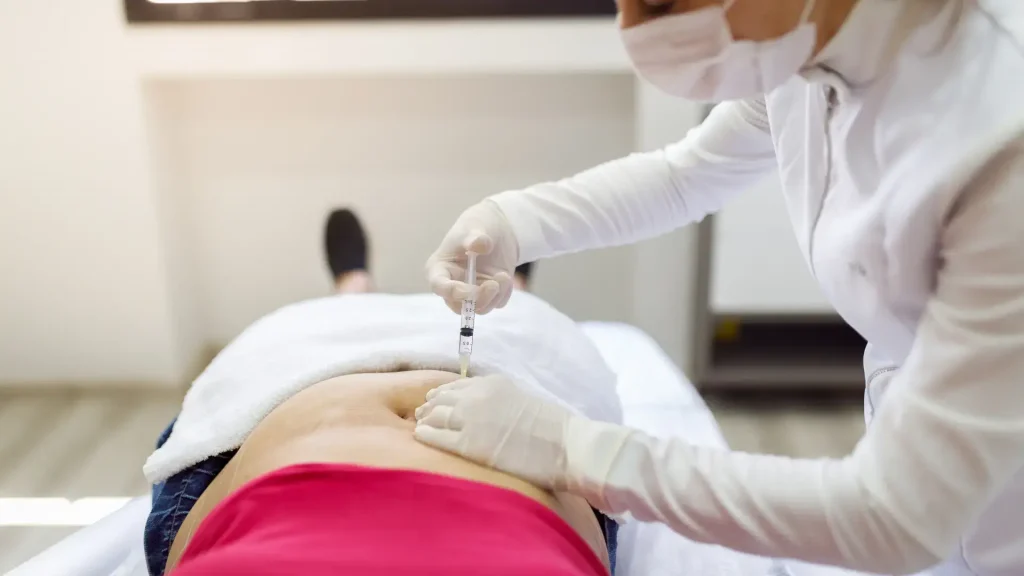 A medical professional administering an injection into the patient's abdomen area.