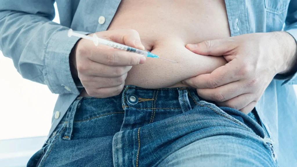 An individual administering an injection into their stomach area.