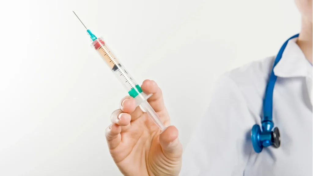 A healthcare provider holding a medical syringe.