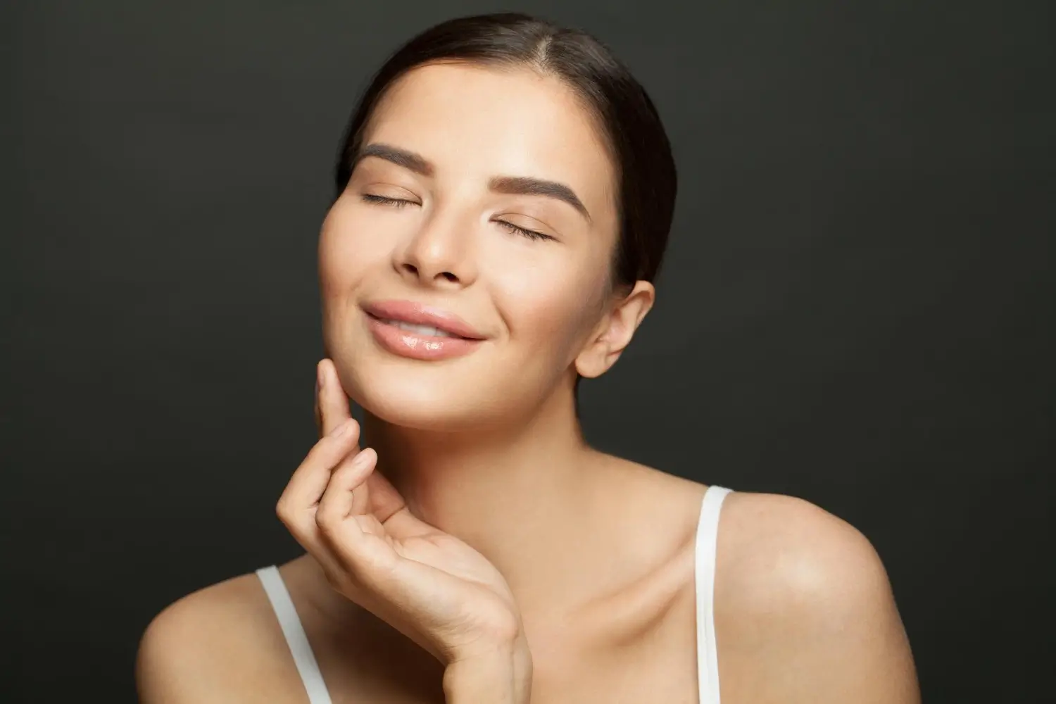 A woman flexing their smooth and clear facial skin.