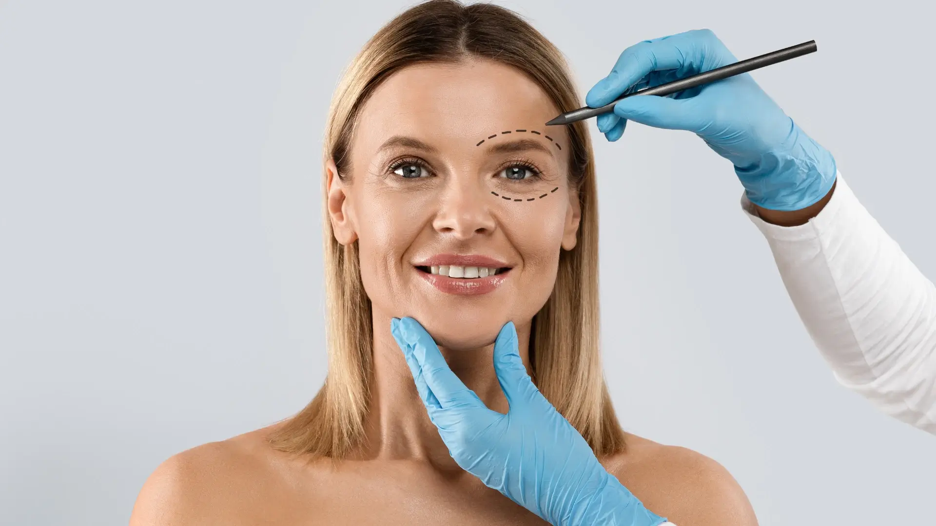 A medical professional marking the treatment area on the patient's eye region.