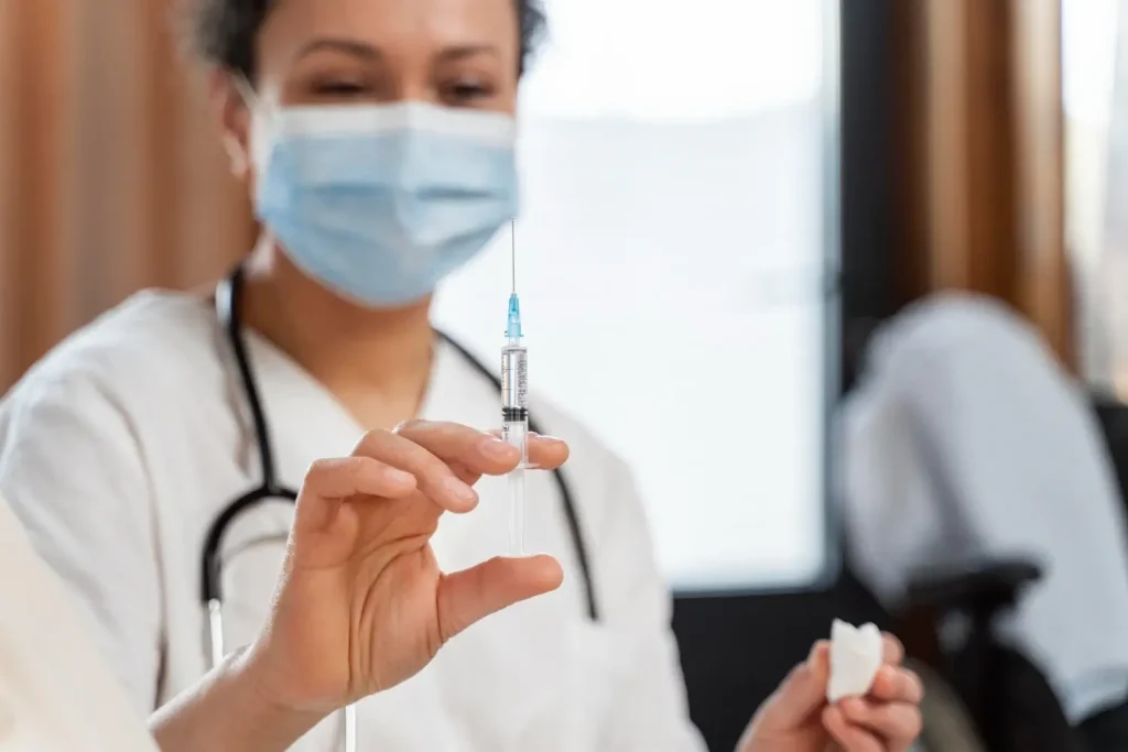 A medical professional holding an injection.