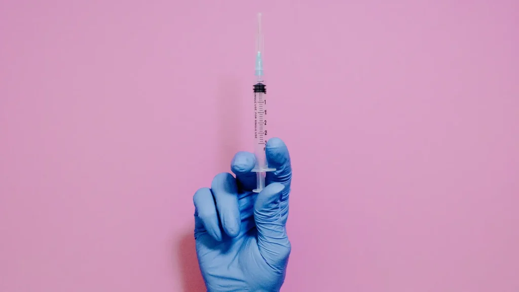 A medical professional holding an injection.