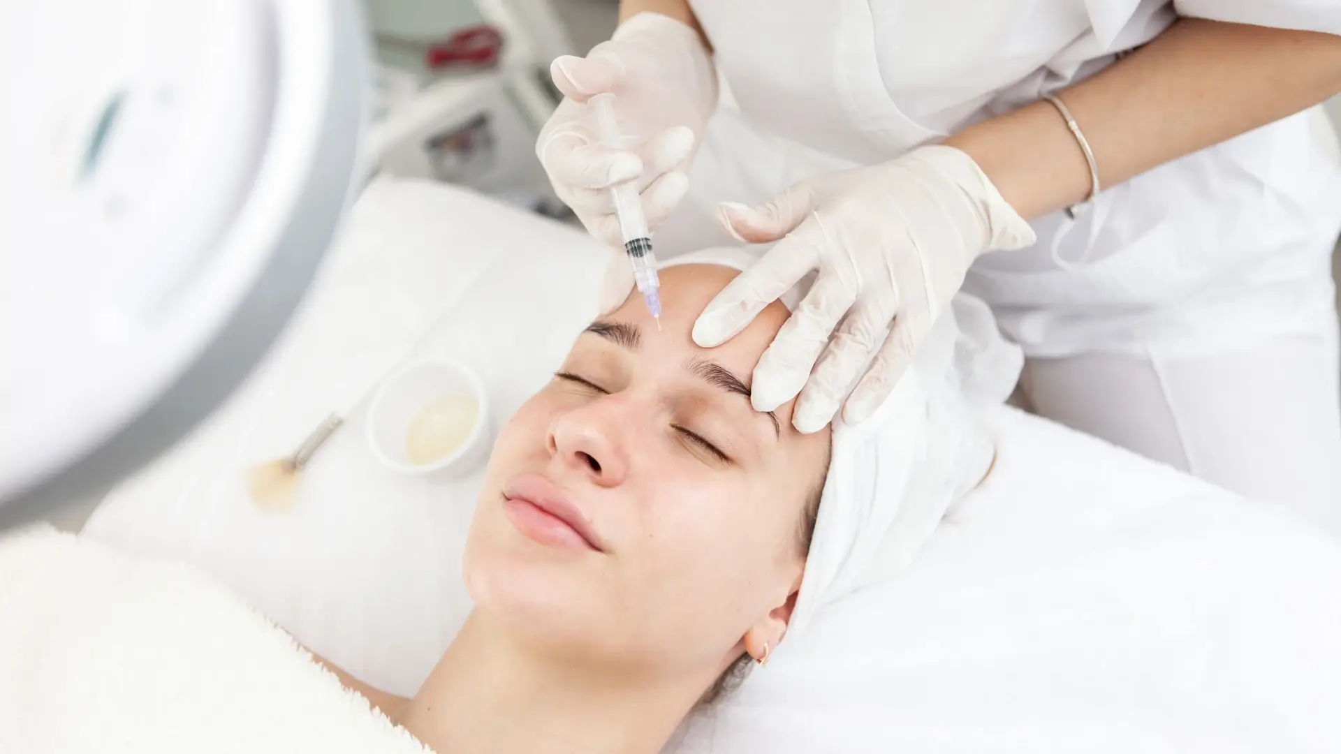 An aesthetic provider administering an injection into a patient's frown lines.
