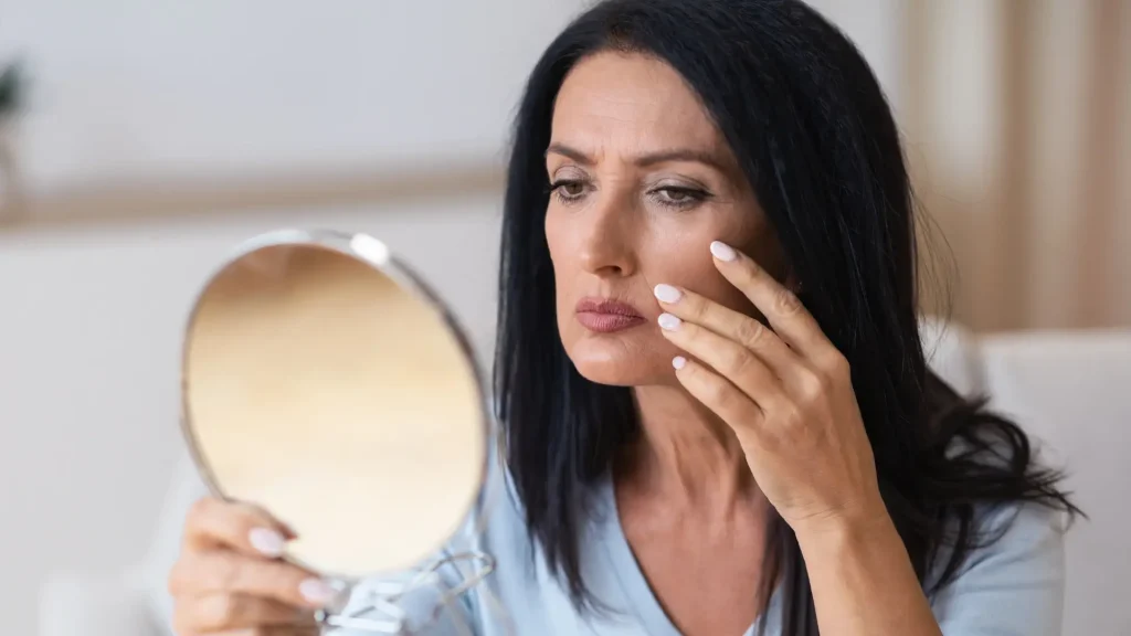 An individual checking their facial skin in the mirror.