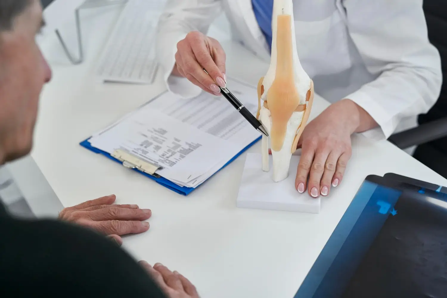 An older individual undergoing a knee consultation with a medical professional.