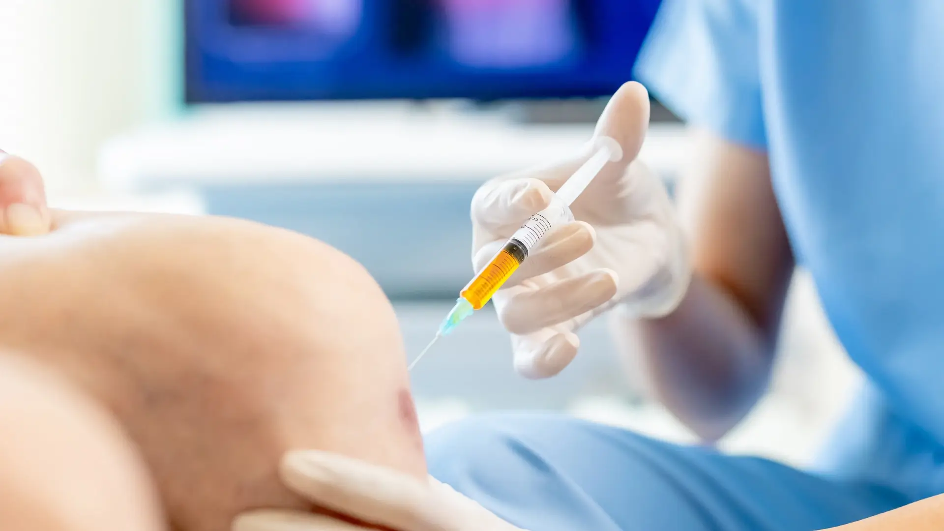 A medical professional administering a knee injection into a patient.