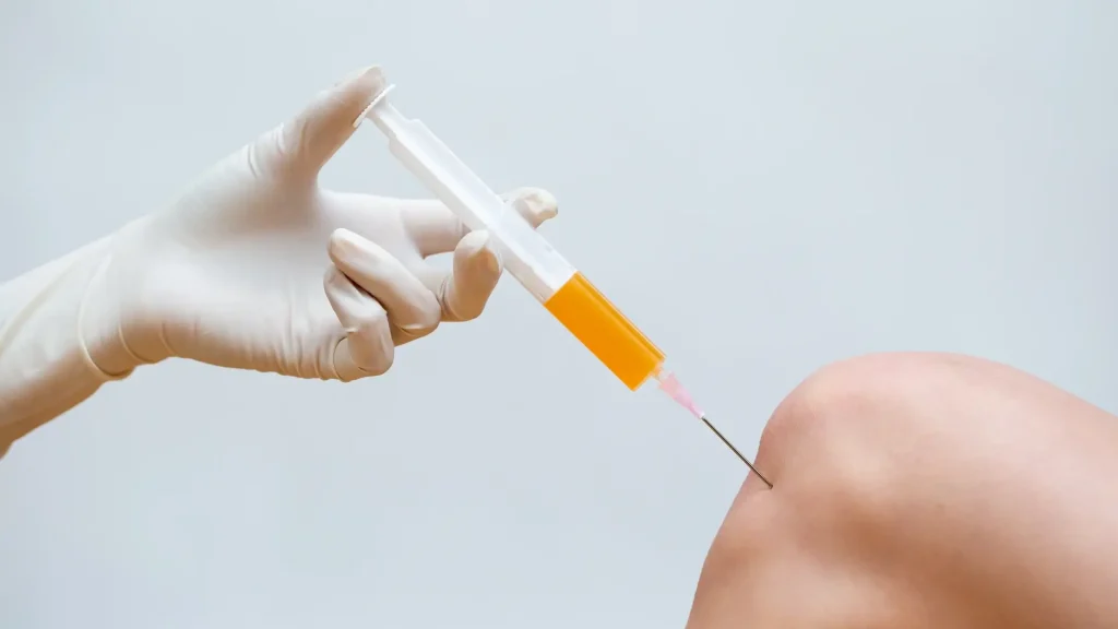 A medical professional administering a knee injection.