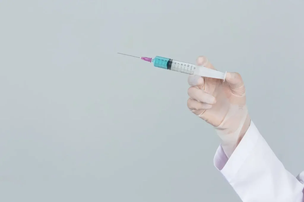 A medical professional holding an injection.