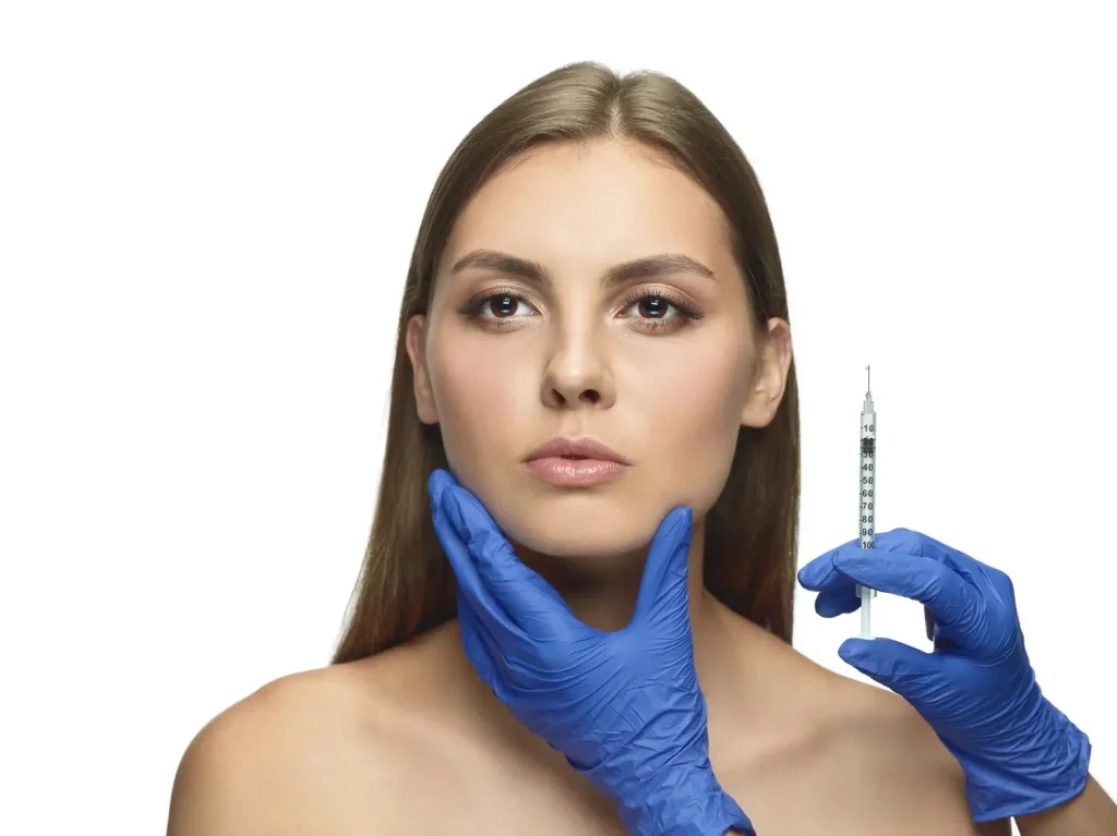 A medical professional holding an injection beside a patient's face before injecting.
