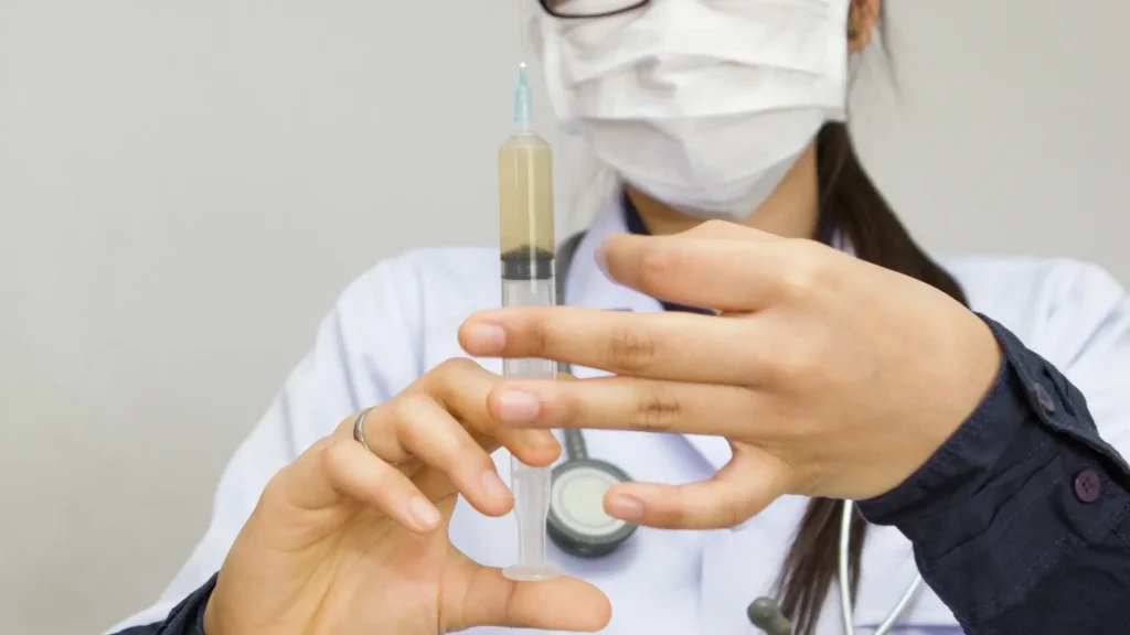A medical practitioner holding an injection.