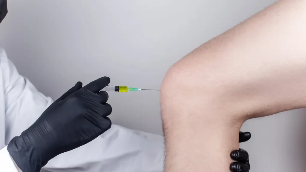 A medical professional administering a knee injection.
