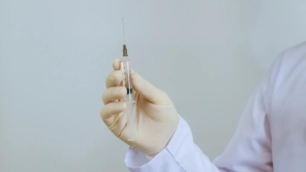 A healthcare professional holding a medical syringe.