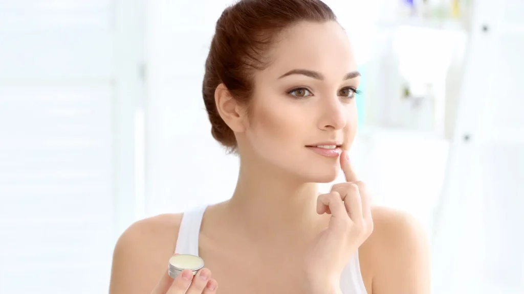 A woman applying skincare to her lips.