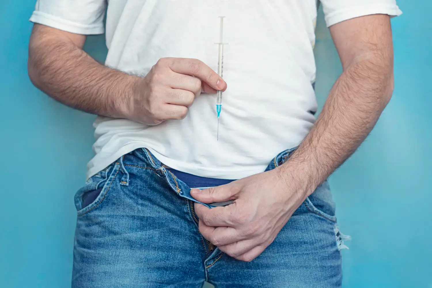 A male individual posing with an injection for their intimate region.