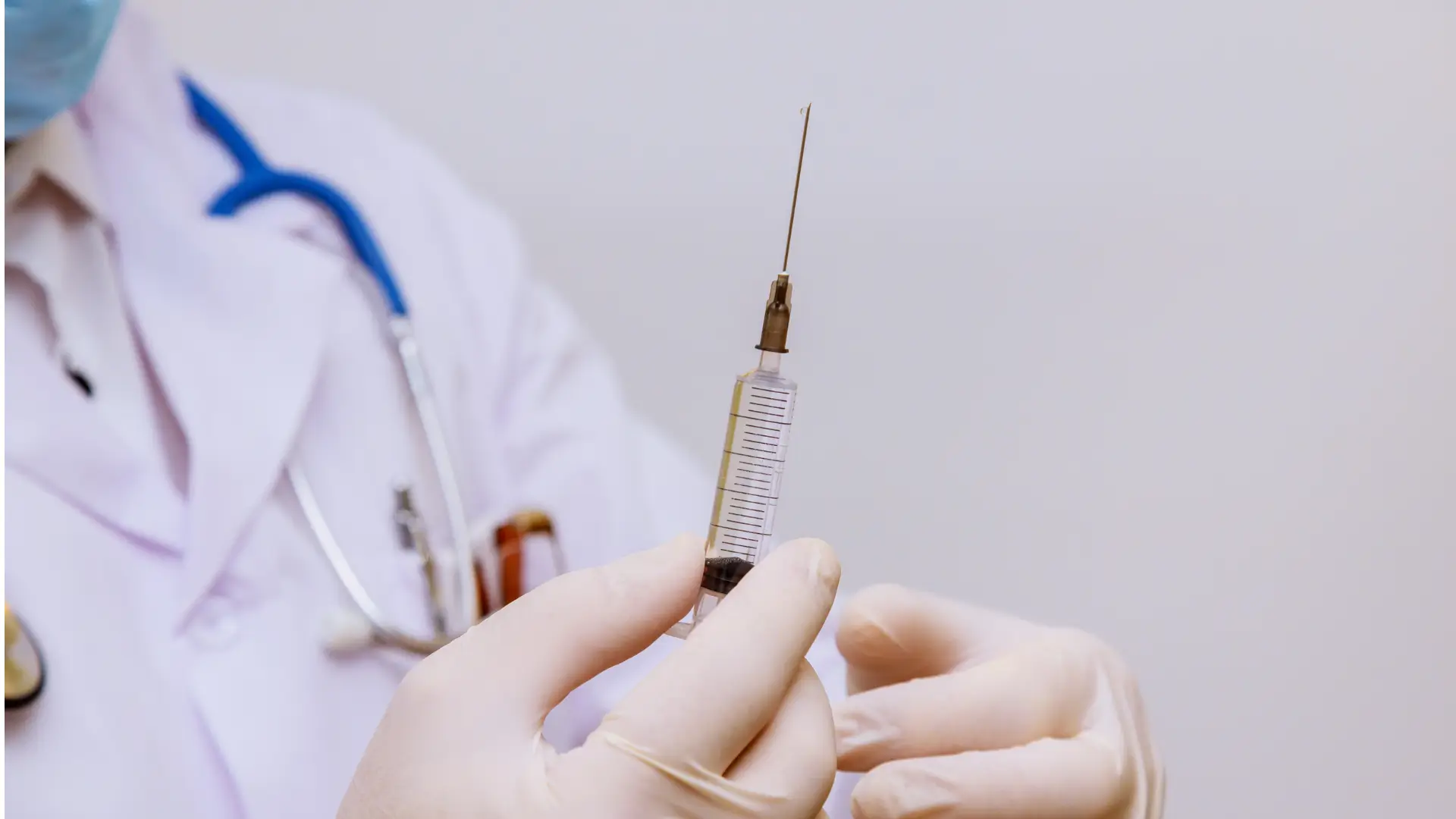 A medical professional holding an injection.
