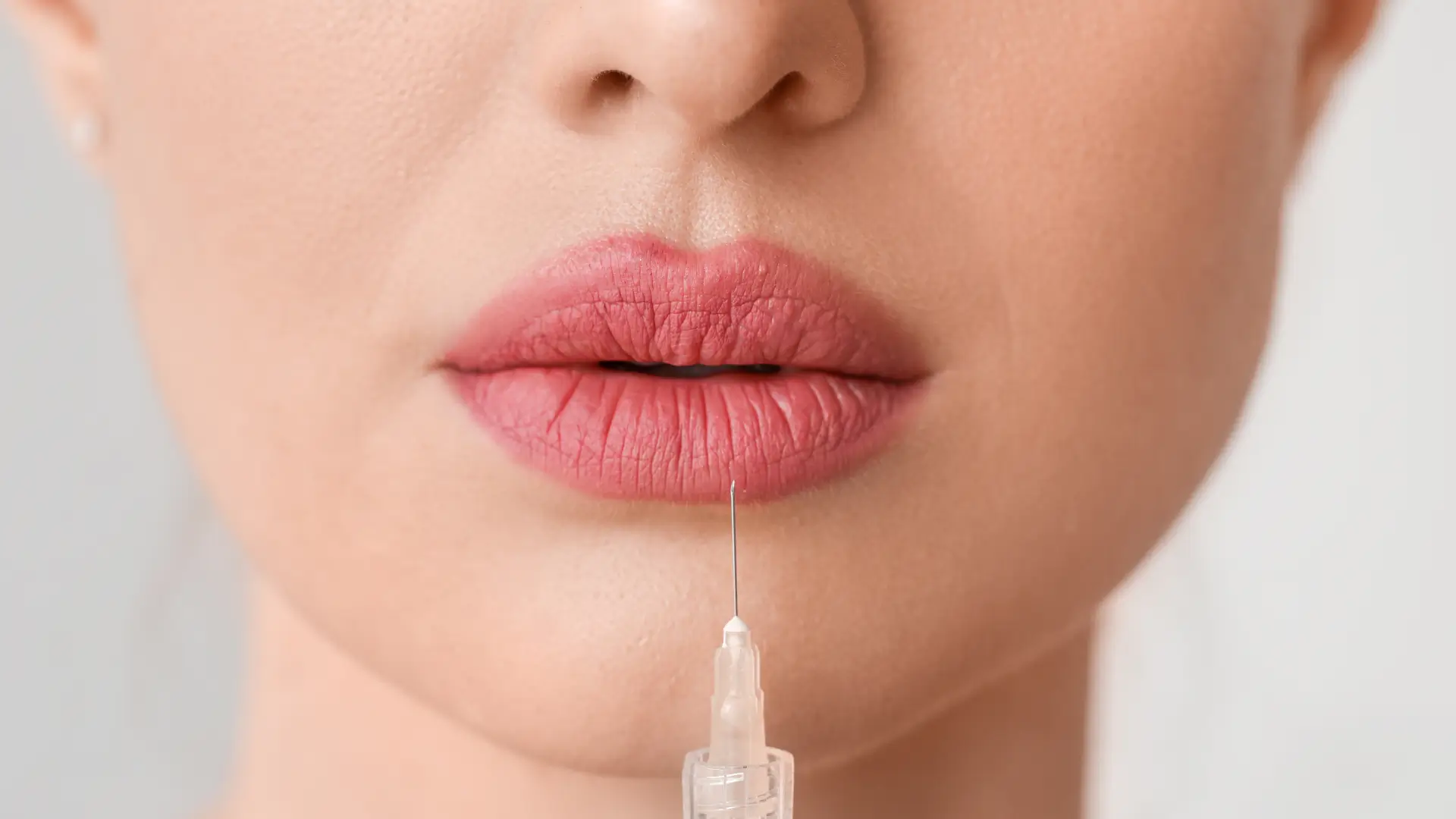A close-up shot of a syringe near the patient's lips before injection.