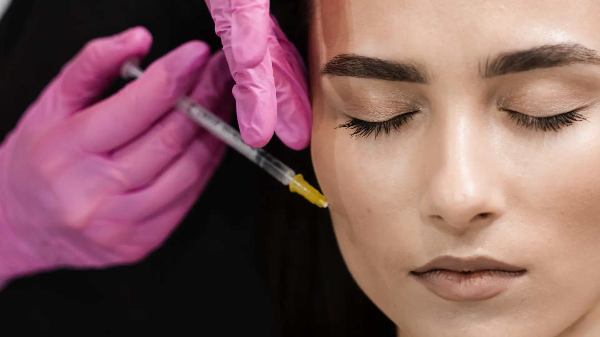 An individual receiving an injection into their midface region.