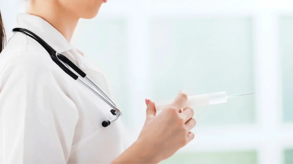 A healthcare professional holding a medical syringe.