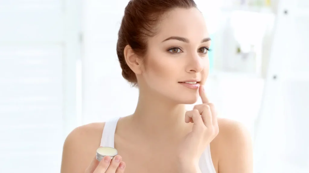An individual applying gentle lip care products to her lips.