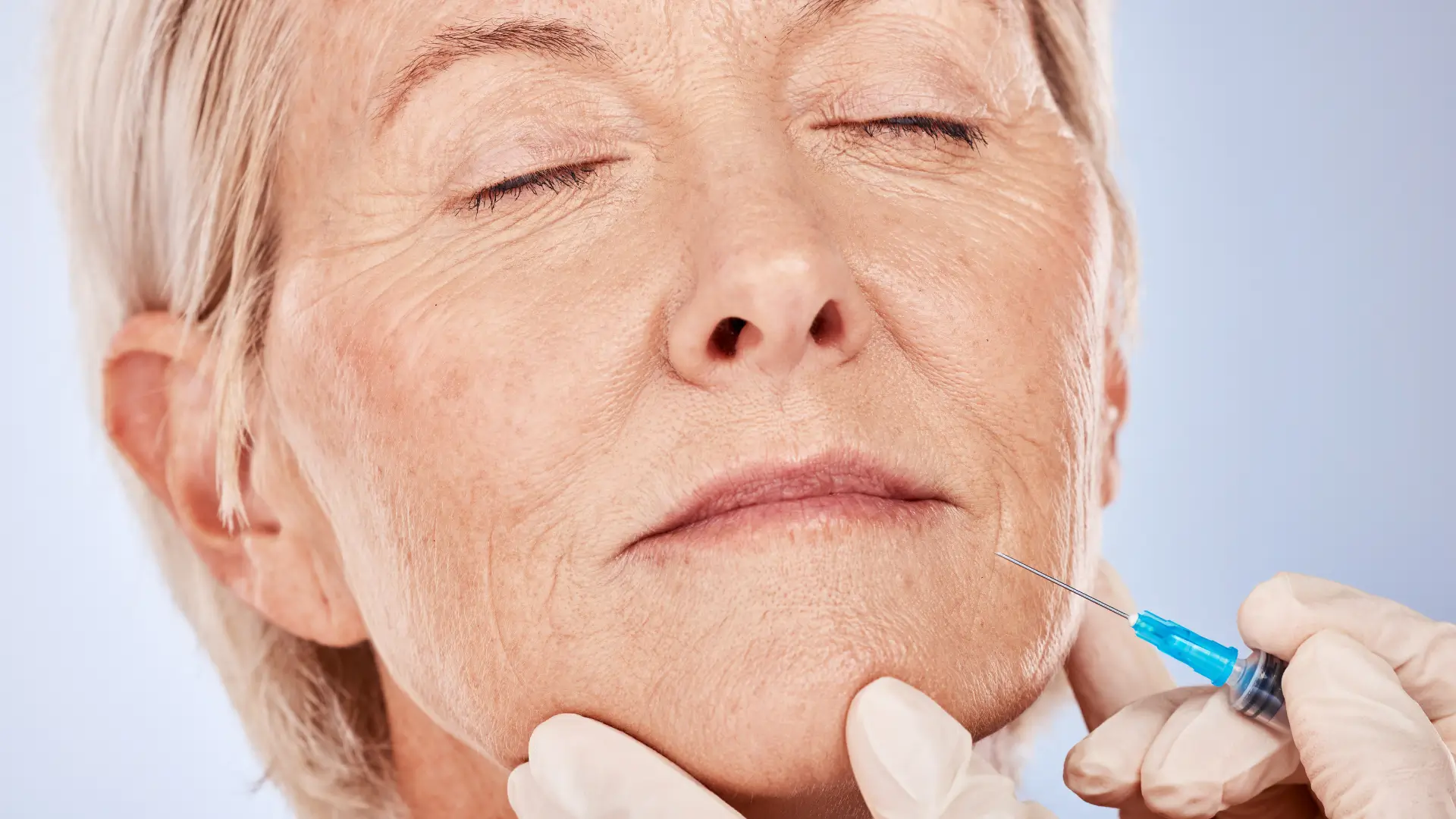 An older individual receiving an injection into their lower face aging lines and folds.
