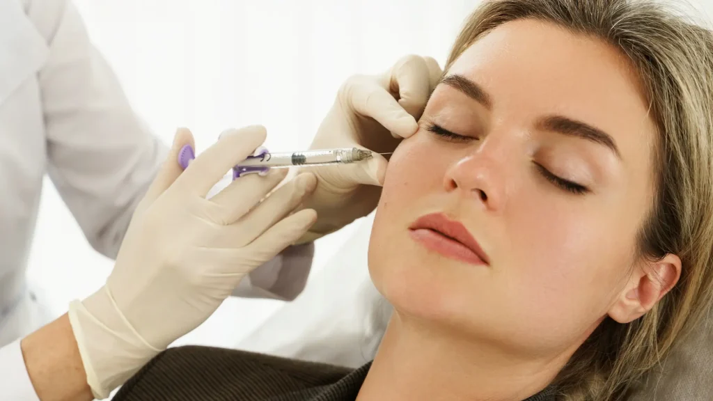 A medical professional administering a dermal filler injection to a patient's midface.