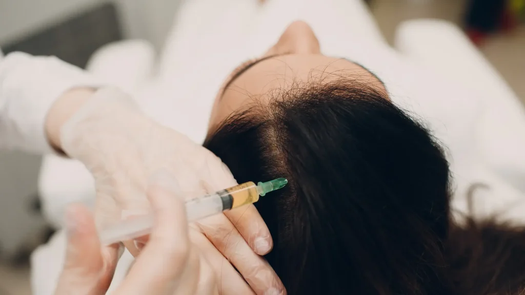 A medical professional administering an injection into a patient's scalp.