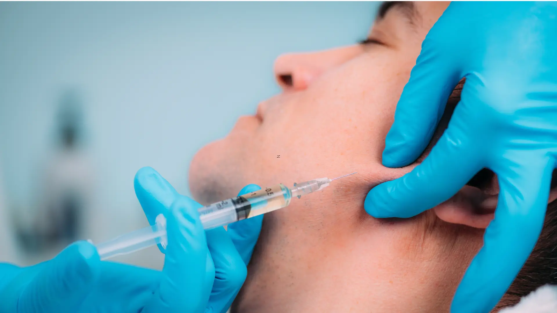 A male individual receiving a dermal filler for their jaw enhancement.