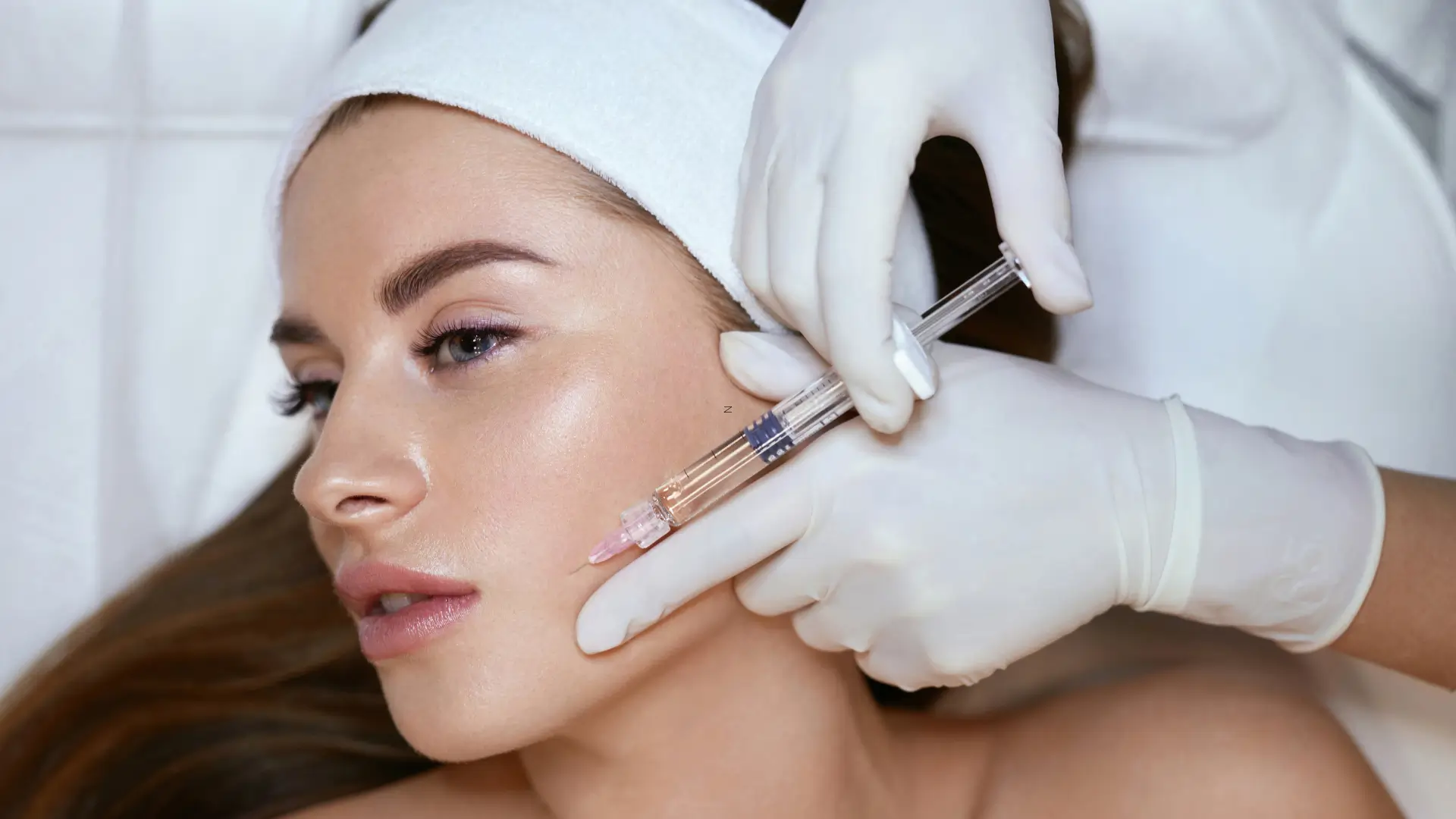 A patient undergoing a dermal filler injection in their midface region.