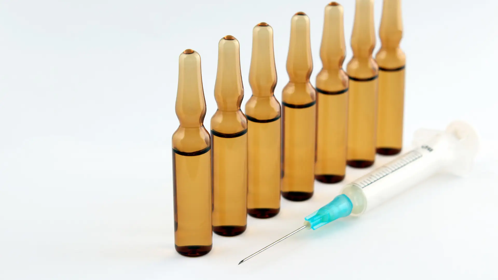 Solution vials lined up and a medical syringe.