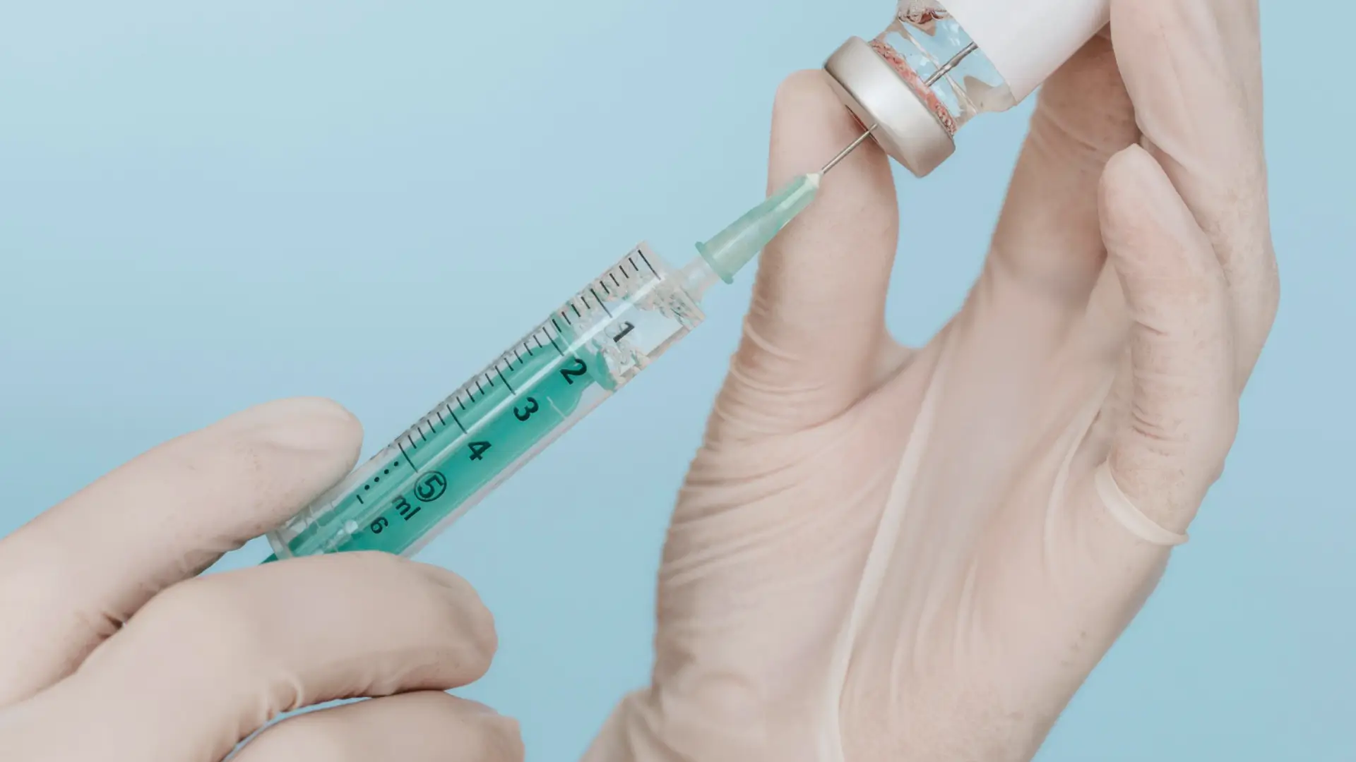 A medical professional preparing the syringe for injection.