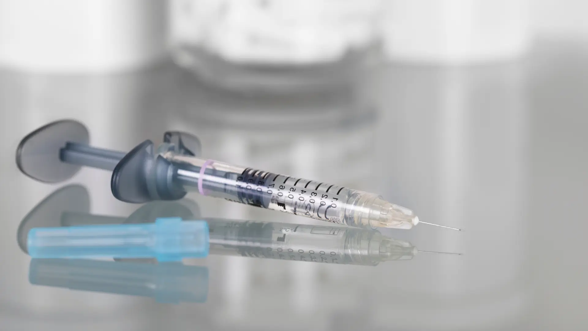 An injection syringe and vial on a surface.